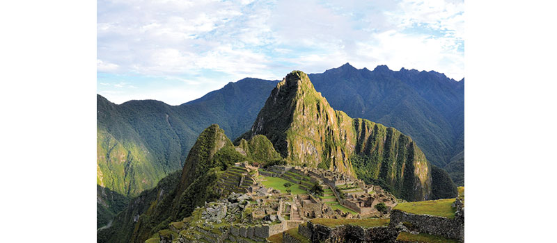 Panorama of Machu Picchu terraces, watcher's hut and Wuayna Picchu with shadow in early morning light.
