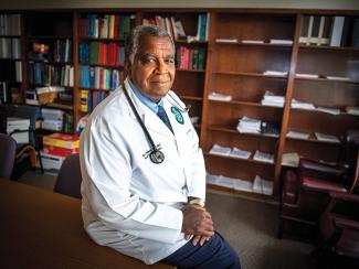 Dr. Keith Ferdinand sits in his office surrounded by books.