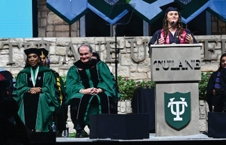 Student speaker Devin Goldman speaks from the podium at Commencement with Sheryl Lee Ralph and President Fitts on stage behind her