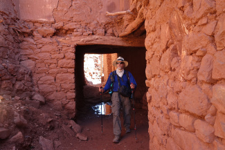 Mark Sindler hikes through an opening in a red rock structure.