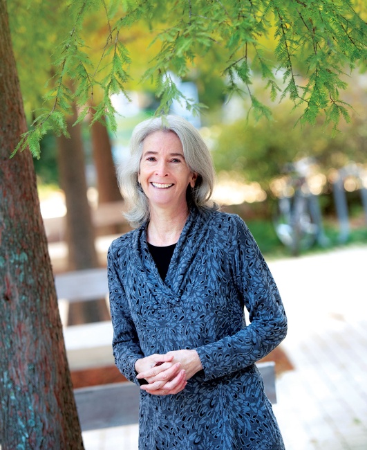 Liz Davey, director of the Office of Sustainability stands with trees near Dinwiddie Hall