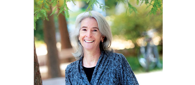 Liz Davey, director of the Office of Sustainability stands with trees near Dinwiddie Hall
