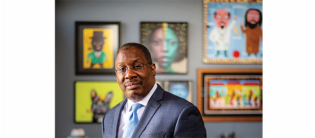 Thomas LaVeist in his office at the School of Public Health. Many paintings are displayed on the wall.