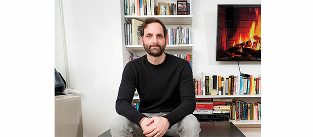 Micah Cohen seated in front of bookcases