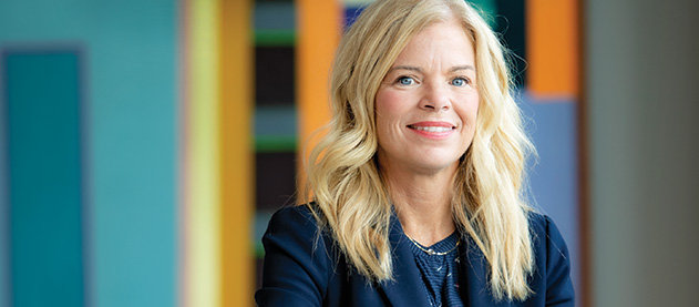 Kimberly Gramm sits at a conference table in front of a contemporary painting