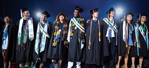 graduates in caps and gowns at the ceremony with night sky