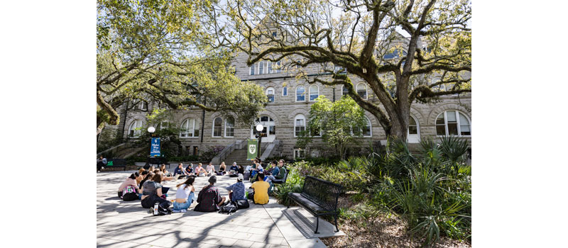 Students sit in class outdoors on the Gibson Quad at Tulane 