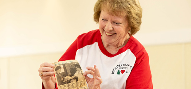 woman holds newspaper clipping from 1980 of heart study