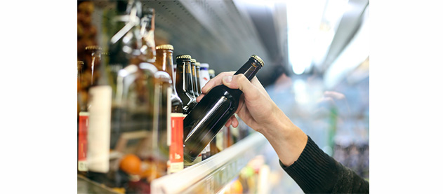close up of hand reaching for a bottle on a grocery store shelf
