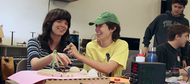 students at a work table with electronic and wooden equipment