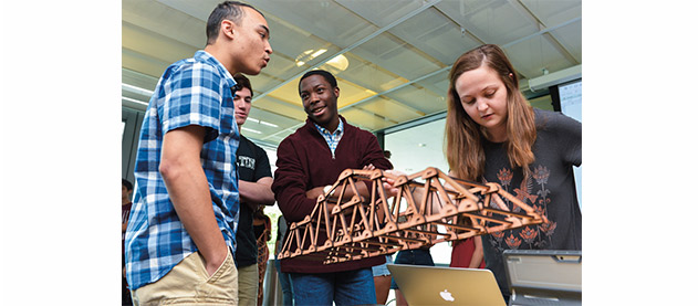 students participate in the Truss-Bust Competition and look at a small model of a structure