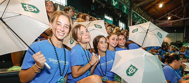 students pose with second line umbrellas in arena stands