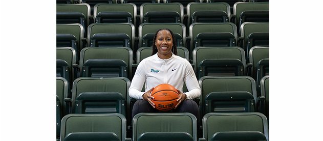 Ashley Langford sits among empty green arena seats and holds a basketball