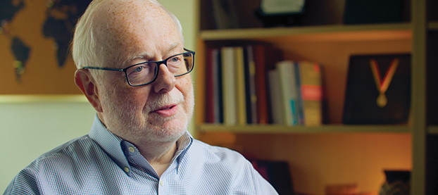 Pierre Buekens sits with a bookshelf in the background