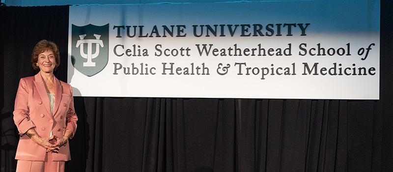 Celia Scott Weatherhead on stage with sign of logo of school