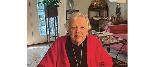 Sue Oppliger portrait sitting and wearing a red sweater