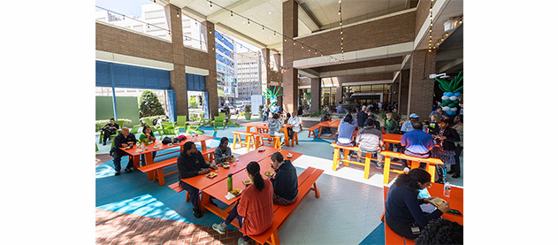 people eating at picnic tables at an open air food court