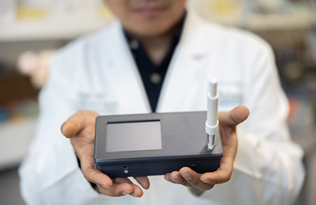 close-up of Tony Hu's hands holding a gray box device