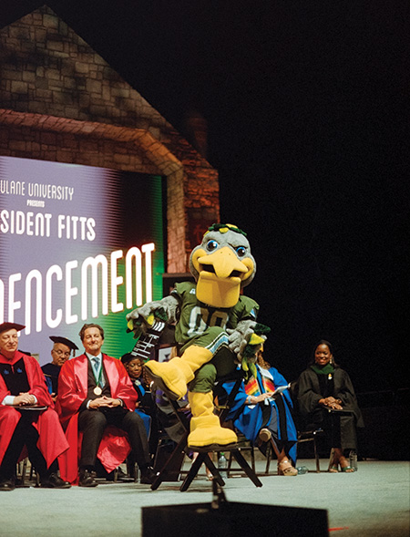 Tulane mascot Riptide the Pelican sits on a film director's chair on stage at Commencement