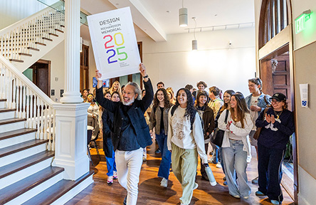 group of people entering RIchardson Memorial Hall interior led by a man with a celebratory sign