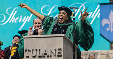 Sheryl Lee Ralph at a graduation podium, wearing academic regalia, gestures energetically. 