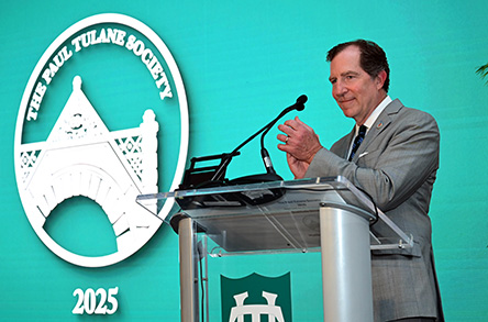 David Mussafer in a gray suit claps at a clear podium against a teal backdrop. The Paul Tulane Society logo and "2025" are displayed prominently.