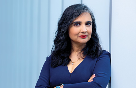 Photograph: Woman with dark hair and arms crossed, looking at camera.