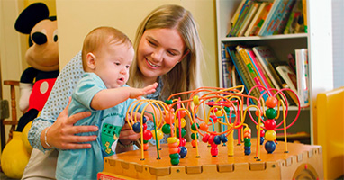 Happy woman and baby playing with a colorful bead maze toy.