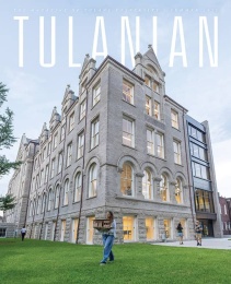 Cover of Tulanian magazine, Summer 2025 issue, featuring a tall, historic stone building on Tulane University’s campus at dusk. Warm light glows from the windows as students walk across the green lawn, including one carrying an architectural model.