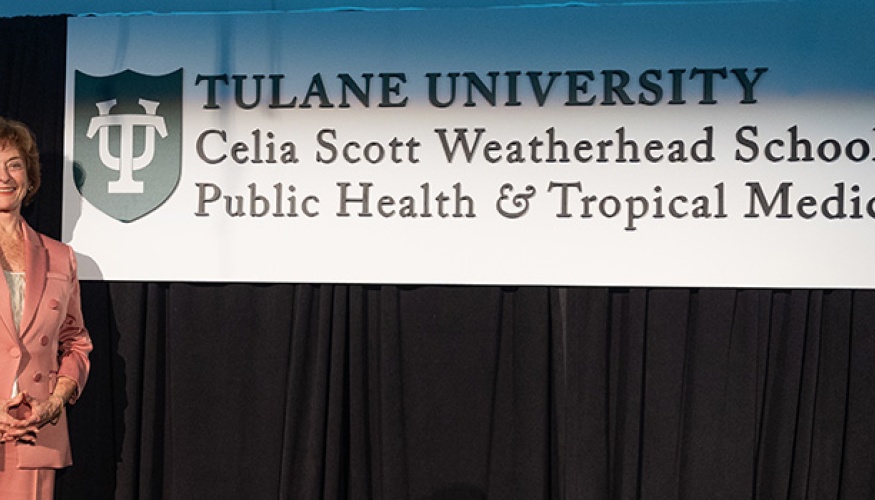 Celia Scott Weatherhead on stage with sign of logo of school