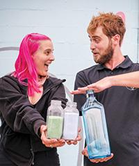 Franziska Trautmann and Max Steitz hold bottles of glass sand