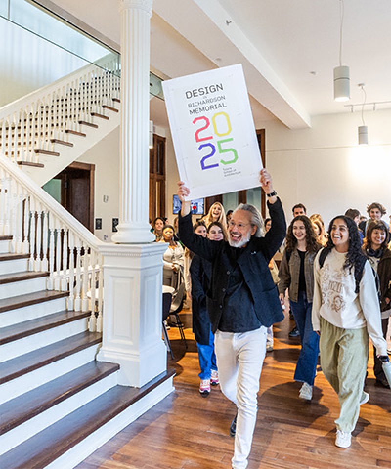 group of people entering RIchardson Memorial Hall interior led by a man with a celebratory sign