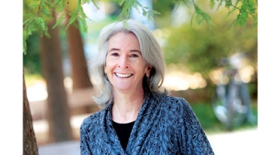 Liz Davey, director of the Office of Sustainability stands with trees near Dinwiddie Hall