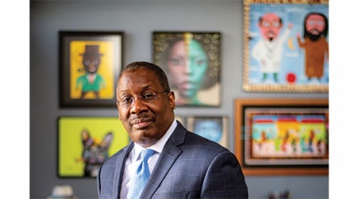 Thomas LaVeist in his office at the School of Public Health. Many paintings are displayed on the wall.