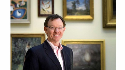 Don Peters poses in front of paintings