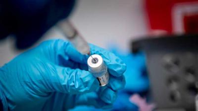 close up of gloved hands preparing a COVID-19 vaccine