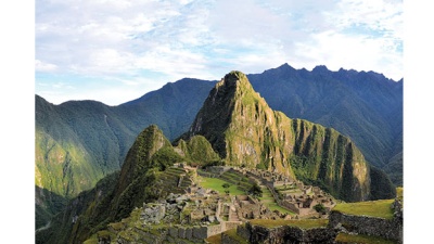 Panorama of Machu Picchu terraces, watcher's hut and Wuayna Picchu with shadow in early morning light.