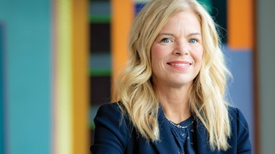 Kimberly Gramm sits at a conference table in front of a contemporary painting