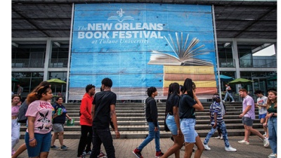 people walk outside past a banner for New Orleans Book Festival on Tulane campus