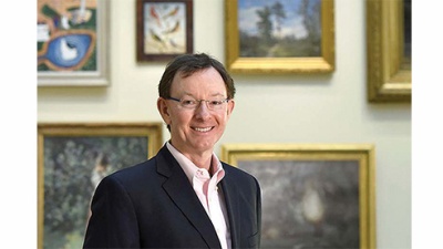 Don Peters poses in room with paintings in background