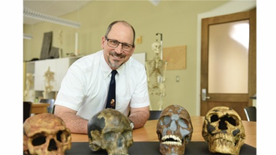 Trenton Holliday surrounded by four replica Cro-Magnon skulls