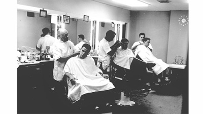 black and white photo of three barbers with customers in chairs in Tulane's barbershop in 1959