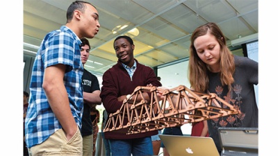 students participate in the Truss-Bust Competition and look at a small model of a structure