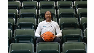 Ashley Langford sits among empty green arena seats and holds a basketball