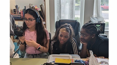 Camila Collazo Rivera mentors three middle school students as they record an announcement