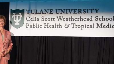 Celia Scott Weatherhead on stage with sign of logo of school