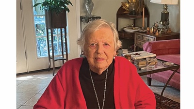 Sue Oppliger portrait sitting and wearing a red sweater