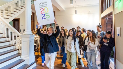 RIchardson Memorial Hall interior Design Celebration group of people entering RIchardson Memorial Hall interior led by a man with a celebratory sign