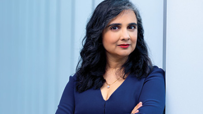 Photograph: Woman with dark hair and arms crossed, looking at camera.