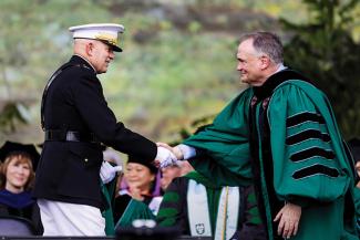 Tulane President Michael A. Fitts shakes hands with General David Berger who appears in uniform.